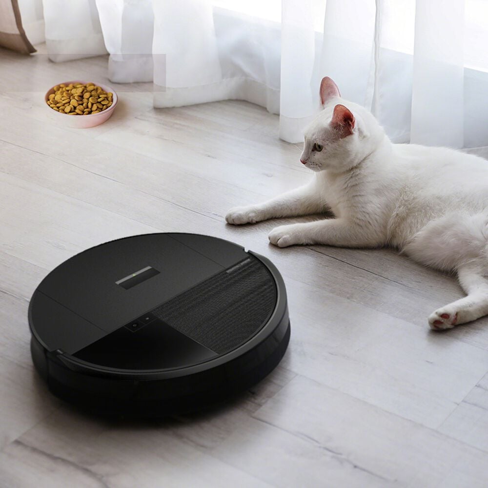A white short-haired cat laying down undisturbed while Roomba&reg; vacuums around it.
