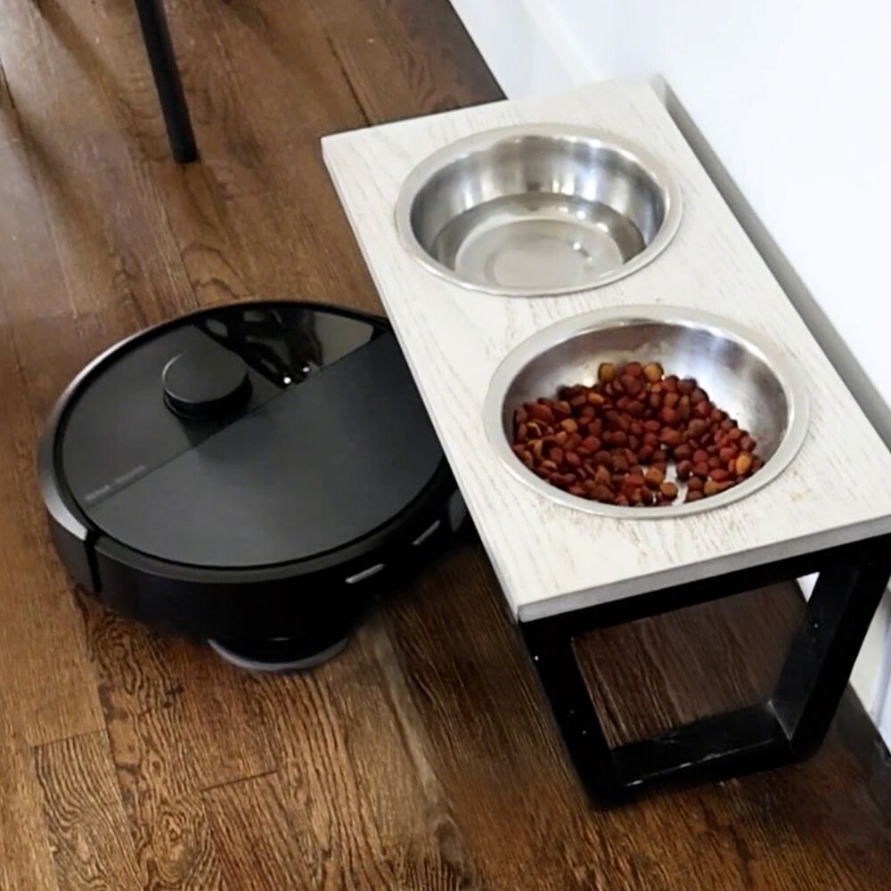 A Roomba&reg; robot vacuuming underneath pet bowl stand.