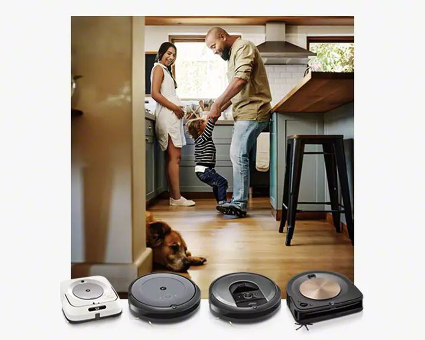A family plays in the kitchen behind images of iRobot’s collection of robot vacuums and mops.